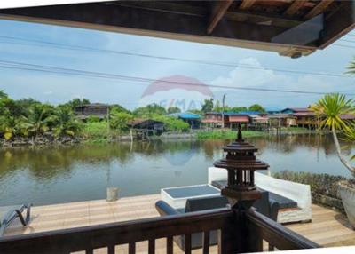 Thai waterfront home with serene shaded surroundings.