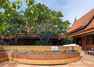 Thai waterfront home with serene shaded surroundings.