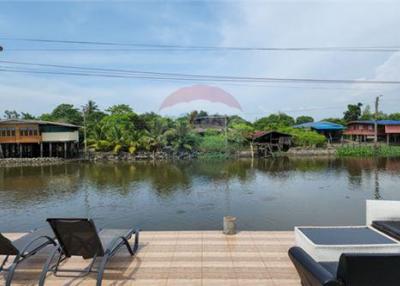 Thai waterfront home with serene shaded surroundings.