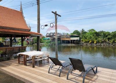 Thai waterfront home with serene shaded surroundings.