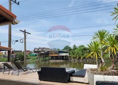 Thai waterfront home with serene shaded surroundings.