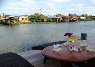 Thai waterfront home with serene shaded surroundings.