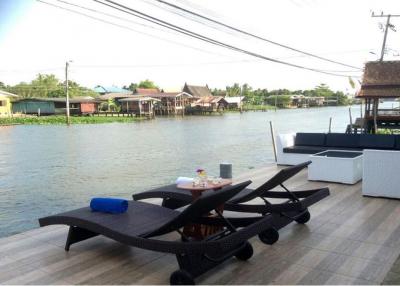 Thai waterfront home with serene shaded surroundings.