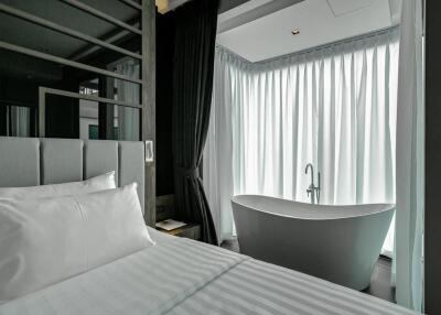 Modern bedroom with an open-concept bathroom including a freestanding bathtub