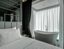 Modern bedroom with an open-concept bathroom including a freestanding bathtub