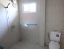 Spacious tiled bathroom with modern fixtures including a shower area, toilet, and electrical water heater