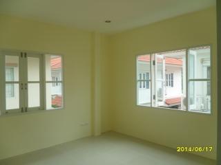 Bright and empty bedroom with two windows showing a residential area
