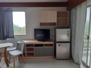 Compact living room with entertainment unit, refrigerator, and dining area