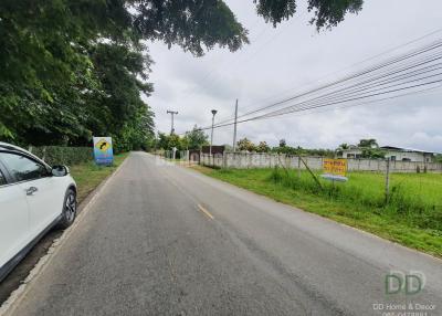 Paved road leading to a property for sale with surrounding greenery