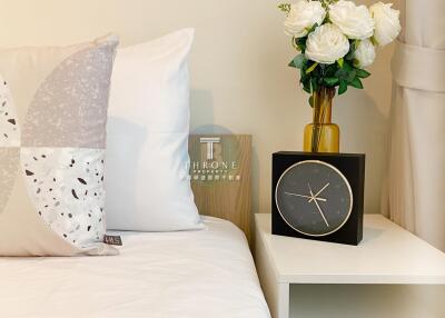 Bedroom with a nightstand, clock, and floral arrangement