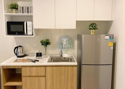 Modern kitchen with wooden cabinets, a stainless steel refrigerator, microwave, and sink