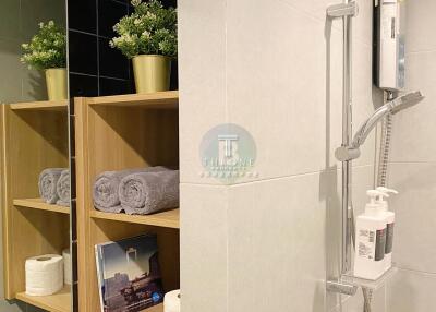 Modern bathroom with shelving, towels, plants, and a shower