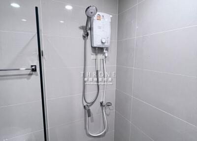 Shower area in a tiled bathroom with an electric water heater