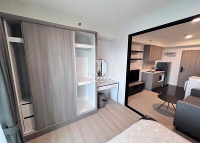 Modern bedroom with open wardrobe and view into the kitchen area