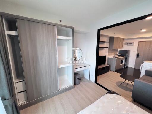 Modern bedroom with open wardrobe and view into the kitchen area