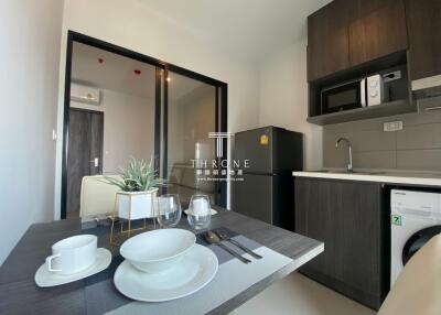 Modern kitchen area with dining table, fridge, microwave, and washing machine