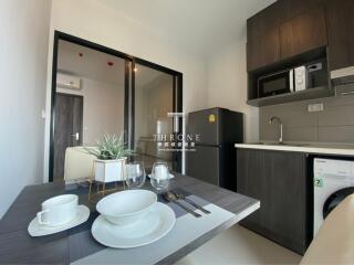 Modern kitchen area with dining table, fridge, microwave, and washing machine