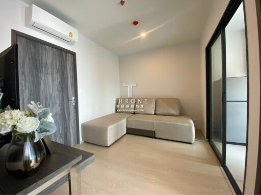 Modern living room with an L-shaped sofa, glass sliding door, and air conditioning unit