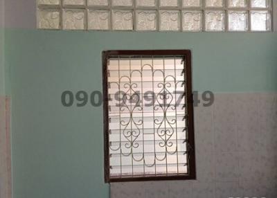 Bathroom with tiled walls and natural light from a small window with decorative iron bars