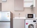 Modern kitchen with stainless steel appliances including a refrigerator and a washing machine