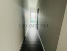Long narrow corridor with wooden flooring leading to a window at the end