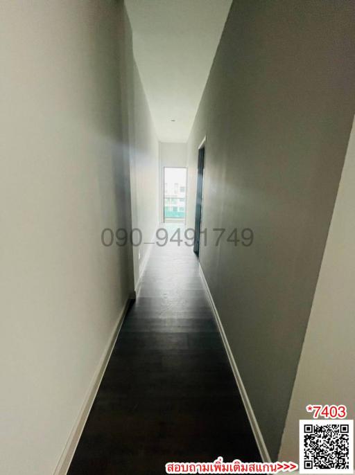 Long narrow corridor with wooden flooring leading to a window at the end