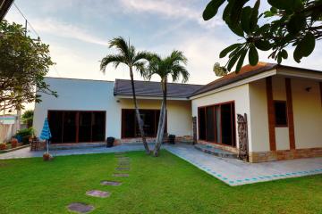 Suburban house with a well-maintained lawn and palm trees