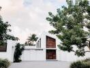 Modern white residential building facade with wooden elements and driveway