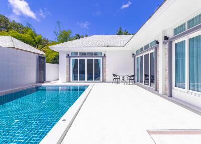 Bright outdoor pool area with a clear blue swimming pool adjacent to a modern house