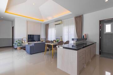 Spacious open plan living room with kitchen, dining area, and entertainment setup