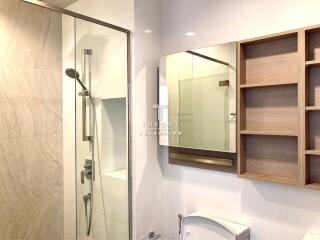 Modern bathroom with shower area, large mirror, and shelving