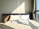 Sunlit bedroom with a neatly made bed next to large windows