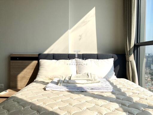 Sunlit bedroom with a neatly made bed next to large windows