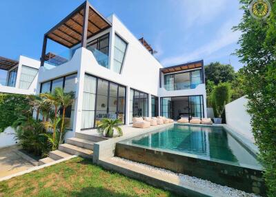 Modern white building with large windows, outdoor seating area, and swimming pool