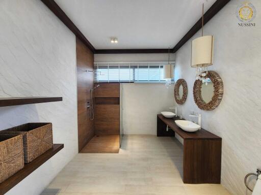 Modern bathroom with double sinks, large shower, and wooden accents