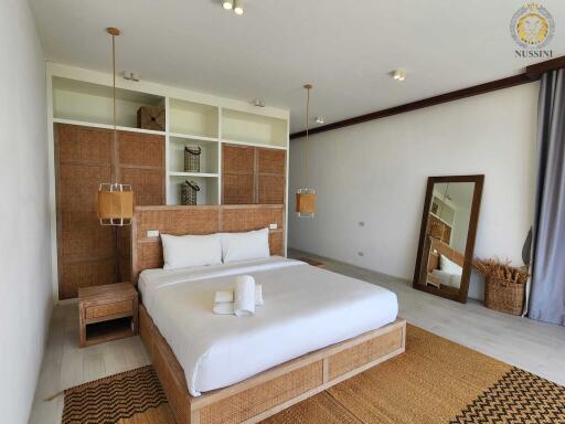 Spacious bedroom with modern decor, wicker furniture, and large mirror