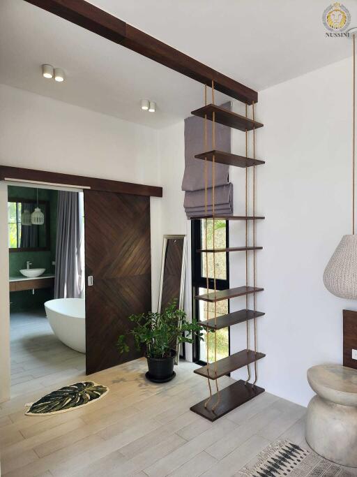 Contemporary interior with bathroom visible through sliding door, plant, hanging bookshelf