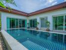 Luxurious home exterior with a large swimming pool and glass doors leading to the interior