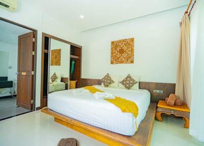 Bright and spacious bedroom with a comfortable double bed, wooden accents, and modern amenities