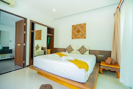 Bright and spacious bedroom with a comfortable double bed, wooden accents, and modern amenities