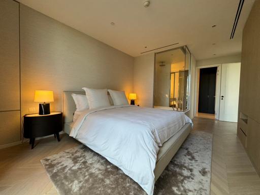 Modern spacious bedroom with a large bed, comfortable bedding, side tables with lamps, and a full-length mirror