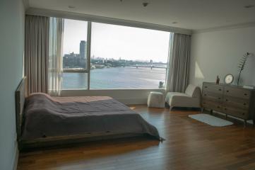 Spacious bedroom with a large window offering panoramic river views and ample natural light
