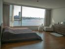 Spacious bedroom with a large window offering panoramic river views and ample natural light