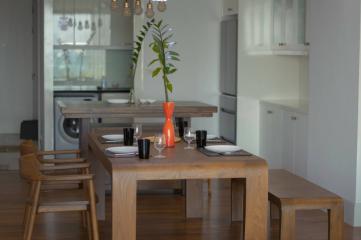 Modern dining room with table set for dinner and open-concept kitchen in the background