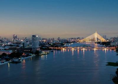 Panoramic evening view of a city skyline with a lit cable-stayed bridge over a river