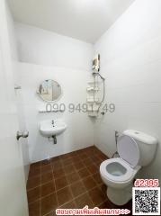 Compact bathroom with white tile walls, brown tile floor, toilet, sink, and mirrored medicine cabinet