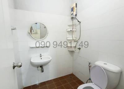 Compact bathroom with white tile walls, brown tile floor, toilet, sink, and mirrored medicine cabinet