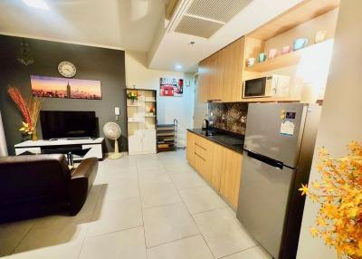 Modern kitchen with integrated living space featuring wooden cabinets and stainless steel appliances