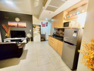 Modern kitchen with integrated living space featuring wooden cabinets and stainless steel appliances