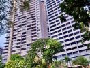 High-rise residential building exterior view with surrounding greenery and pool